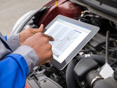 Close-up Of Mechanic With Digital Tablet Showing Graph While Examining Car